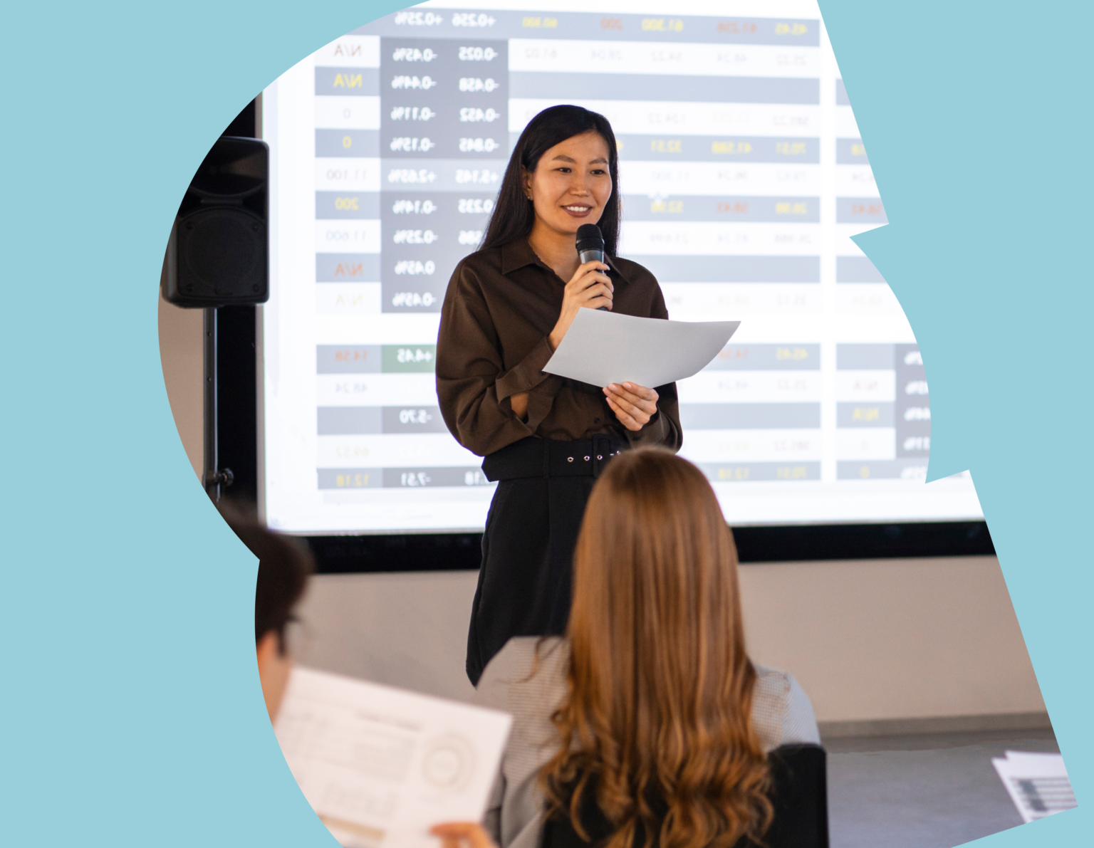 Asian woman with microphone and paper in hand giving a lecture.